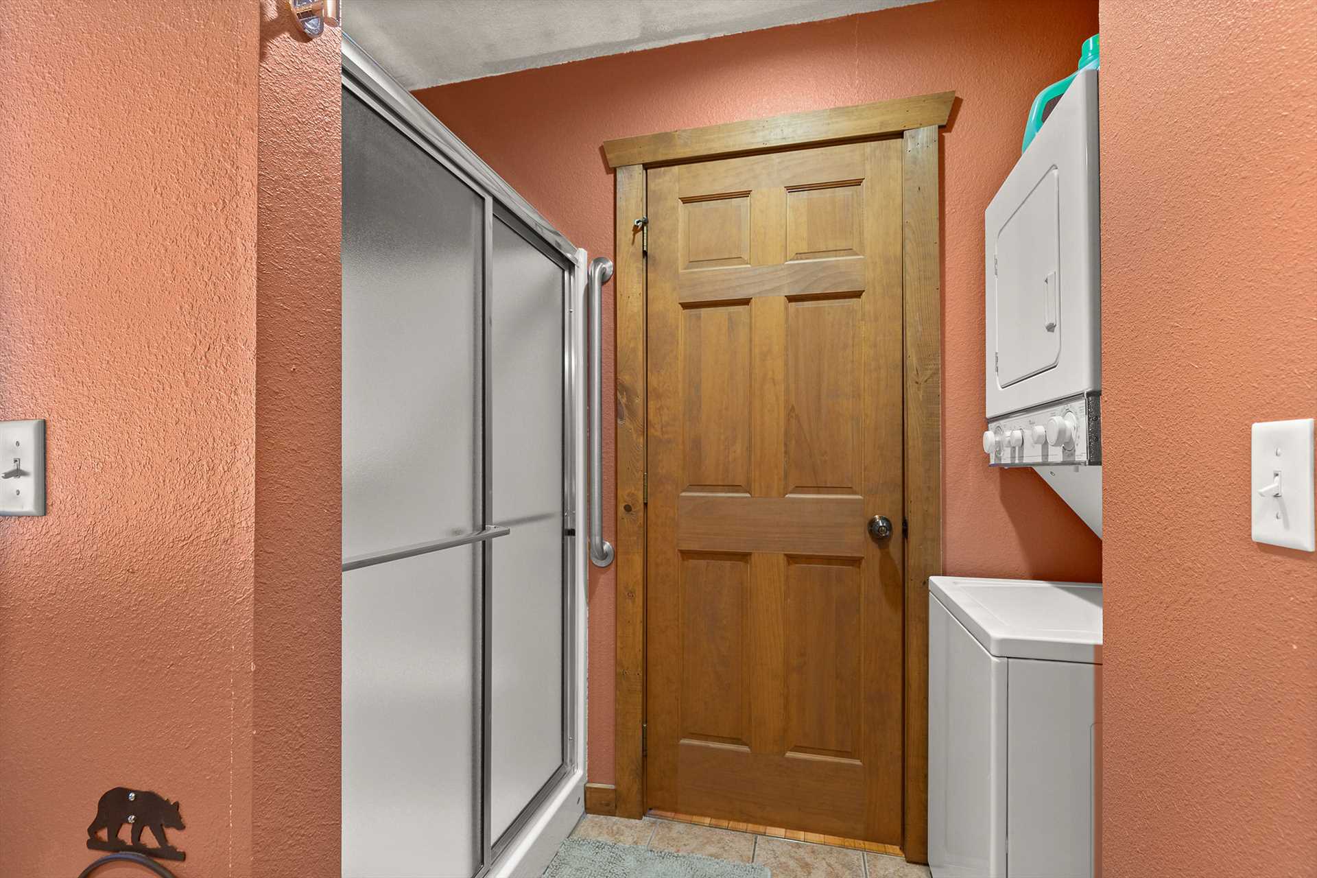 This bathroom has a stacked washer and dryer and connects to