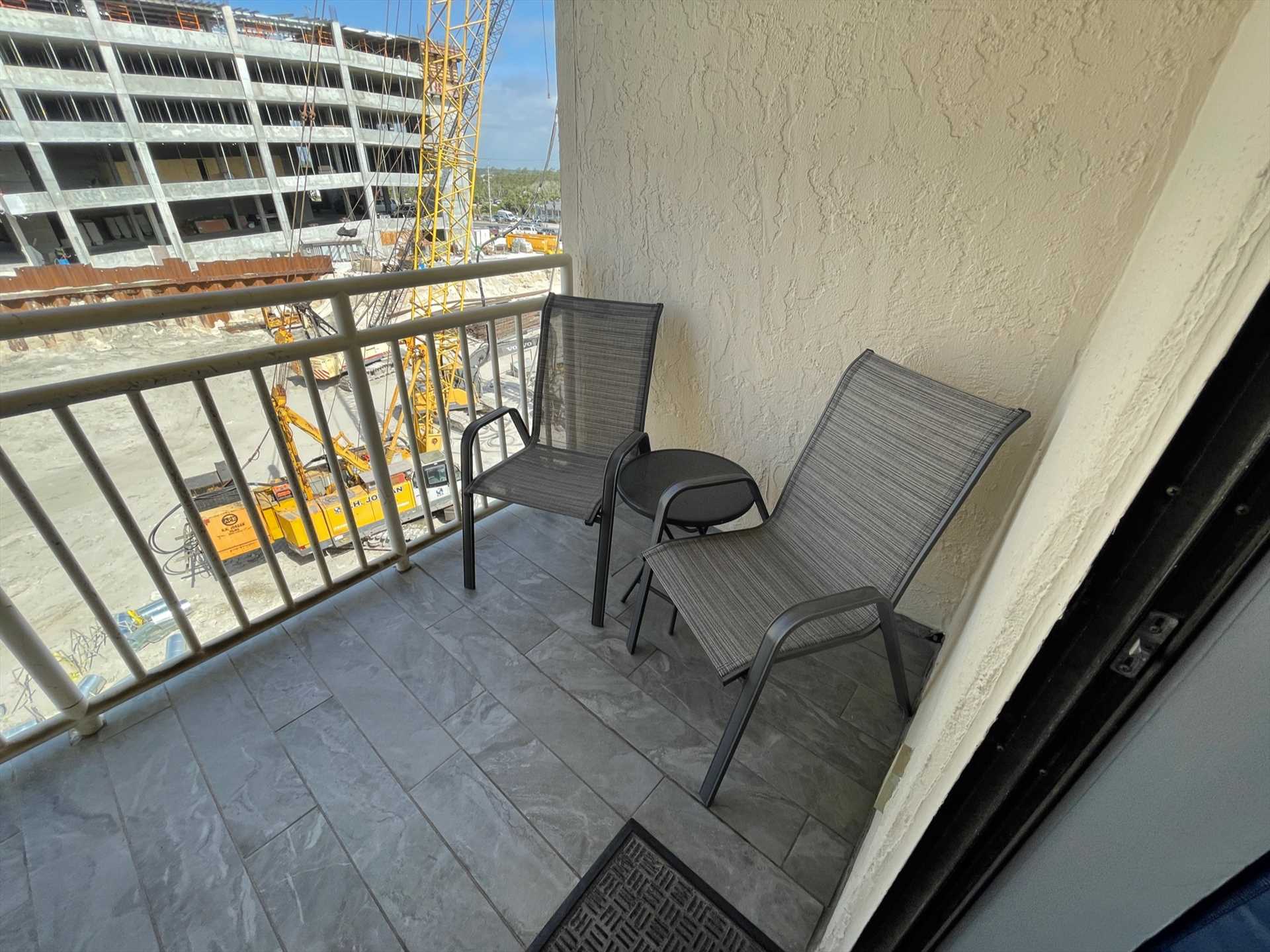 The living room opens up to a small deck space with chairs.