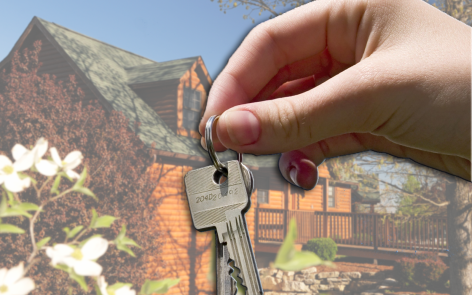 hand holding house Keys in front of vacation home