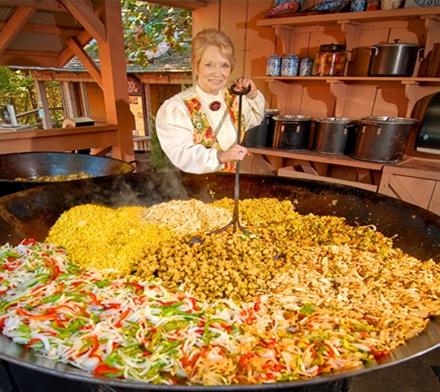 woman stirring a huge skillet of ingredients for a meal