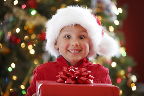 smiling child in Santa hat holding a present
