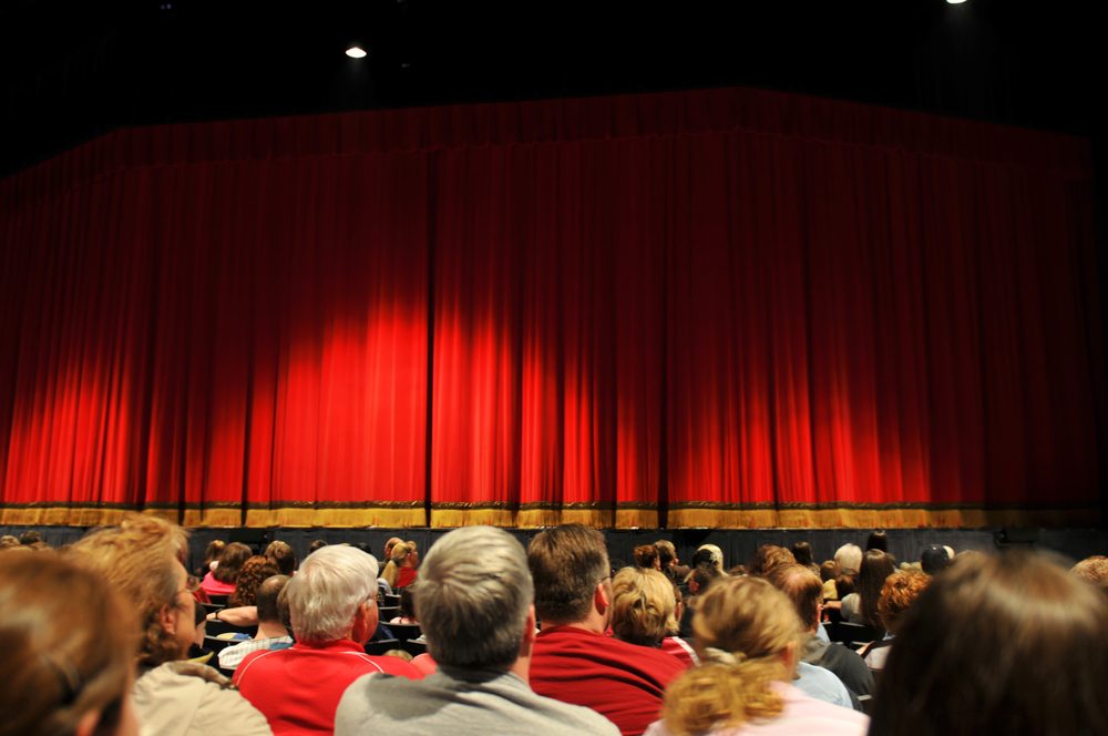 Audience waiting for a show to start, looking at red curtain