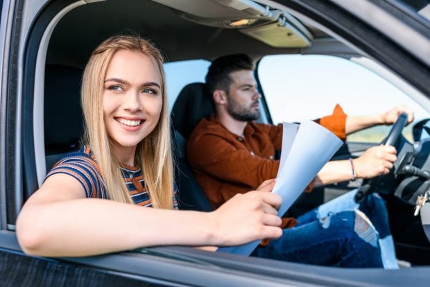 couple in car on a road trip, holding a map
