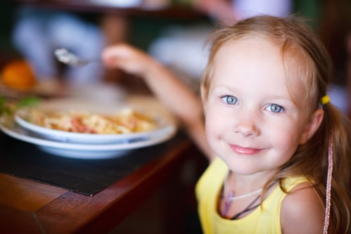 A closeup of a little girl eating at a table