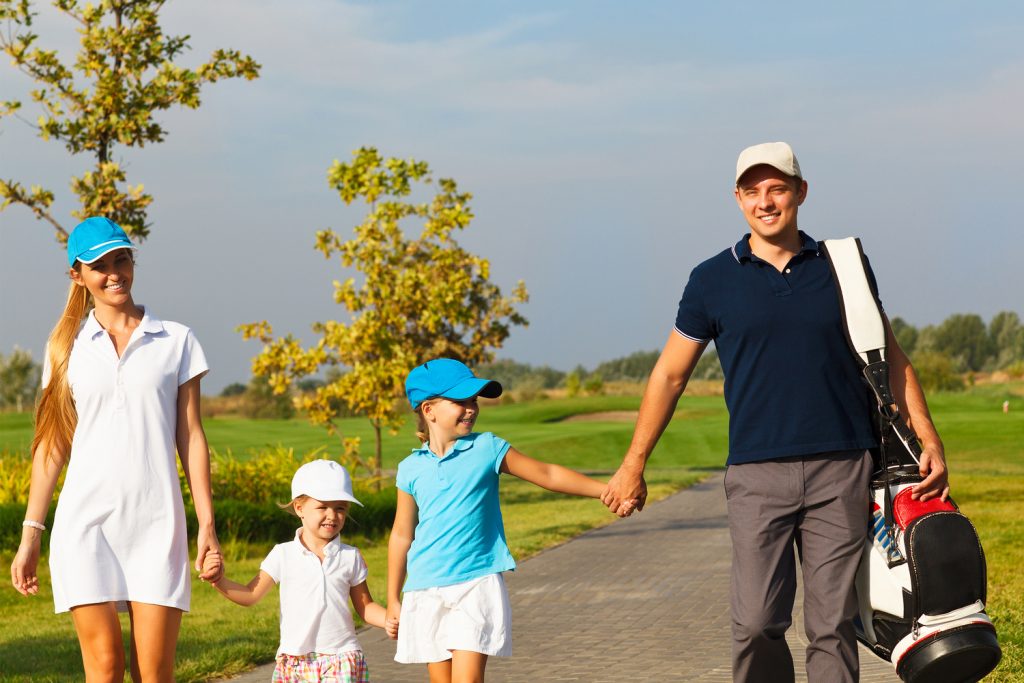 A happy family of golfers walks and-in-hand to their next tee.