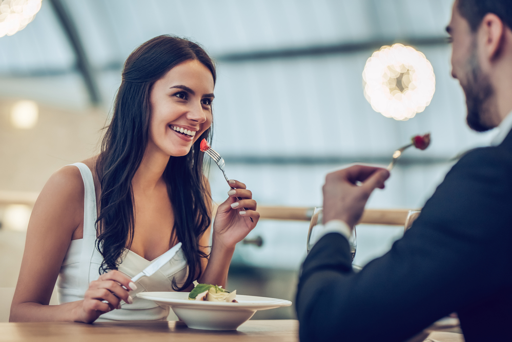 Young couple smiling, enjoying a meal in a nice restaurant