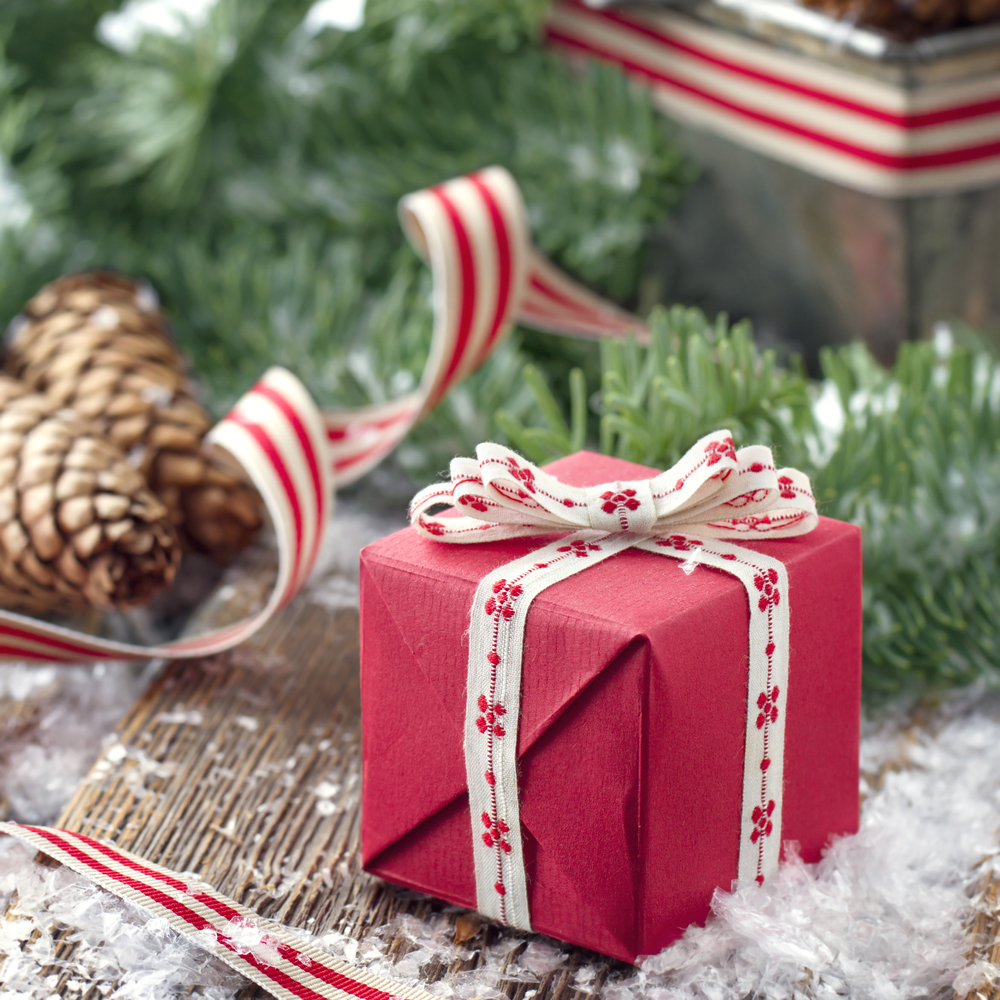 Brown pine cones, Xmas present and green spruce tree branches with snow in a decorative rustic Christmas setting on vintage wooden background