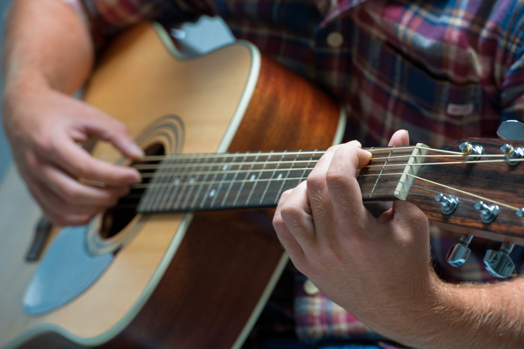 close-up of a male musician playing acoustic guitar