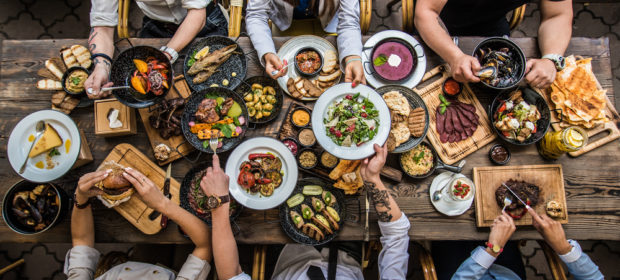 overhead view of long family table with people eating and sharing food.