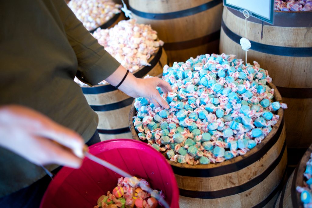 A woman reaches for blue salt water taffy in barrel